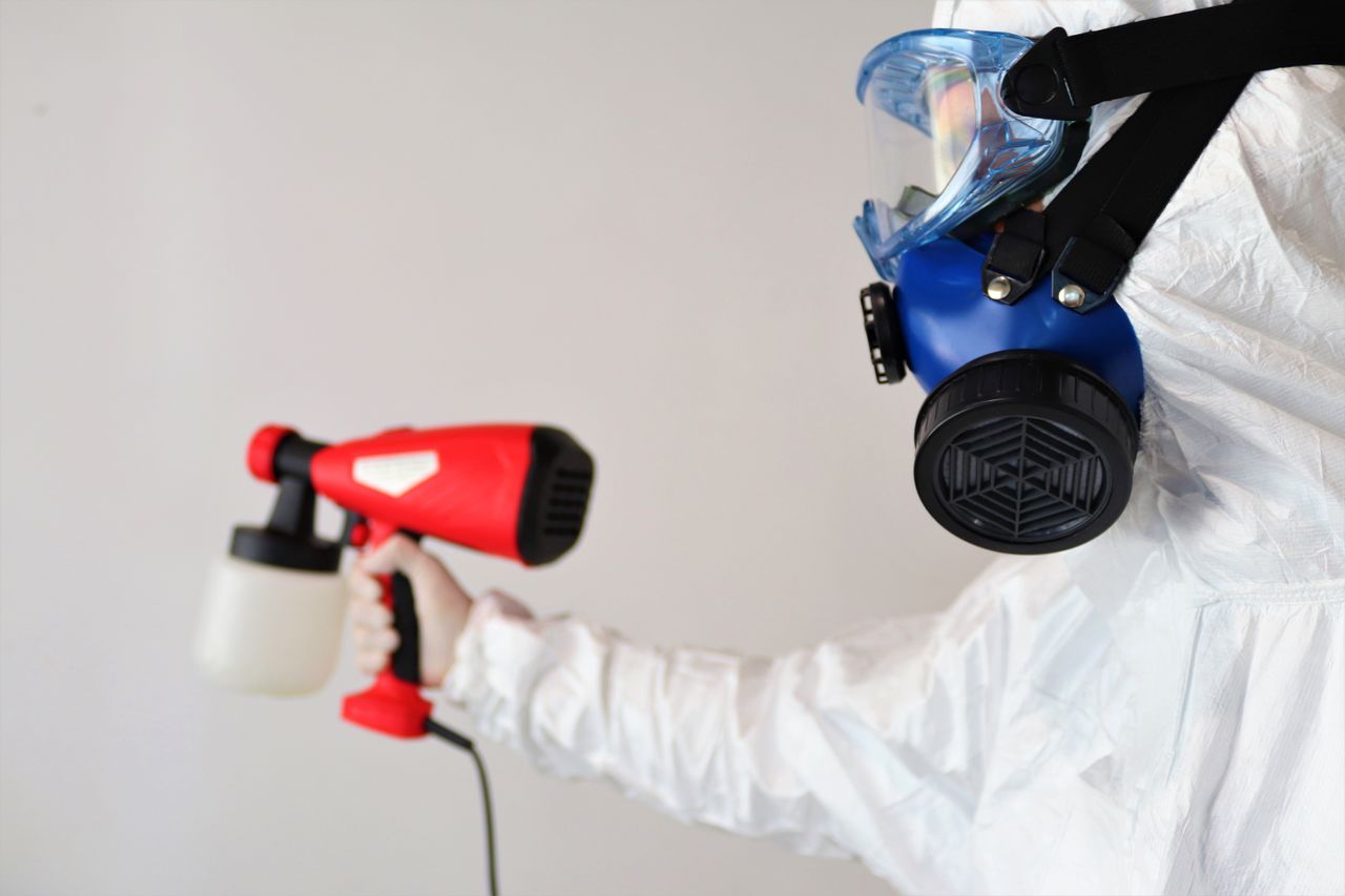 about-us A worker in protective gear uses a disinfectant spray indoors.